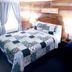 Evening Shade River Lodge & Cabins in Chimney Rock, guest room with patterned quilt and wood-paneled walls