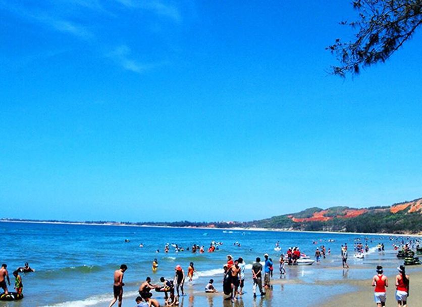 Hon Rom Central Beach Resort in Mũi Né with guests on a sandy beach and calm blue sea