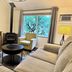 Bramblebank Cottages in Harrison Hot Springs living room with fireplace, sofa, armchair, TV, and forest view
