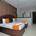 Hotel Meena Paradise, Visakhapatnam guest room with double bed, orange accents, and wall-mounted TV