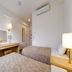 Hotel AZ Kumamoto Hokubu guest room with two beds, desk, TV, mirror and wall-mounted AC in Kumamoto