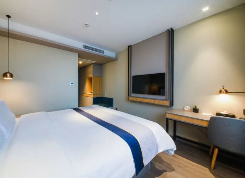 Motel168 Shanghai Qi Bao Inn guest room with bed, desk, wall-mounted TV and modern lighting in Shanghai