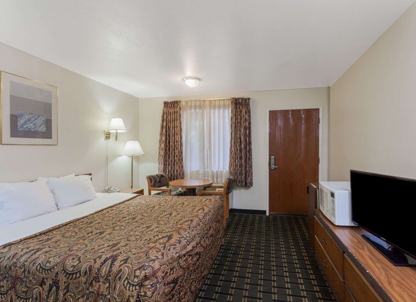 Days Inn by Wyndham Anaheim West guest room with king bed, TV, microwave, and window seating in Anaheim