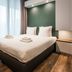 Yays Amsterdam North By Numa bedroom with double bed, large window and modern green accent wall in Amsterdam