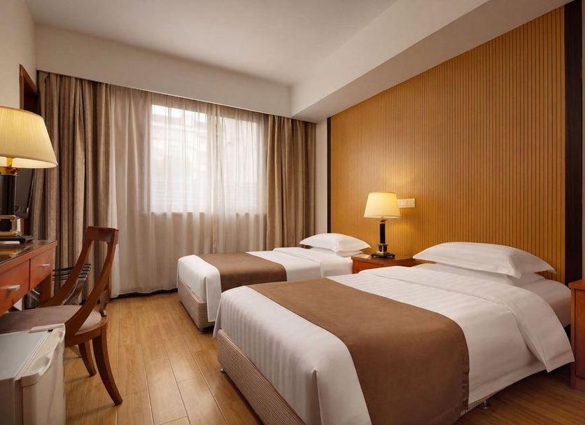 Shanghai Nanquan Hotel Shanghai guest room with two single beds, desk, lamp, and window with curtains