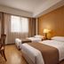 Shanghai Nanquan Hotel Shanghai guest room with two single beds, desk, lamp, and window with curtains