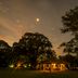 Puerto Valle Hotel De Esteros at dusk, glowing pavilion beside trees with a calm water view