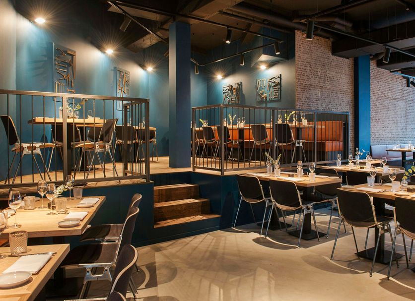 Conscious Hotel The Tire Station Amsterdam restaurant with tables, chairs and elevated seating area