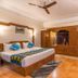 Himgiri Resorts in Dharamshala guest room with king bed, wooden wardrobe, ceiling fan and tiled floor