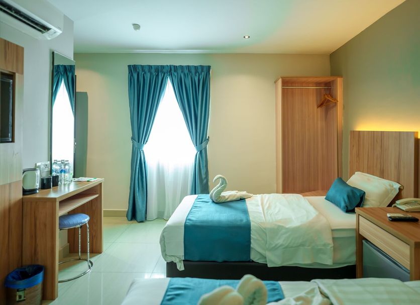 Alaxis Hotel Kuala Lumpur guest room with twin beds, desk, and blue curtains