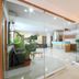 Hotel De Ecobiz in Ahmedabad lobby with glass walls, potted plants, and a lit wall art display