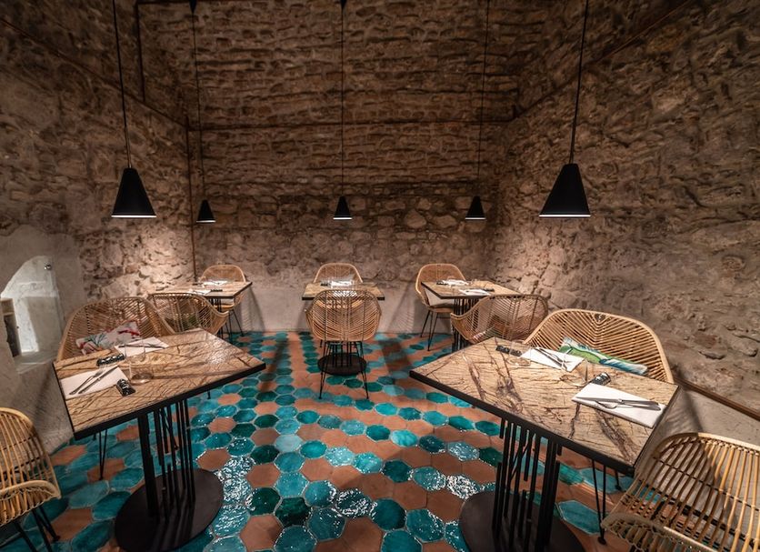 Médousa Suites in Taormina, stone-walled dining room with woven chairs and patterned tile floor