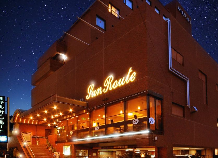 Hotel Aisul Matsuyama exterior at night in Matsuyama, with glowing SunRoute sign and lit entrance