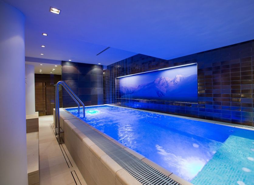 Indoor pool at Hotel Angela in Lech am Arlberg with blue lighting and tiled walls