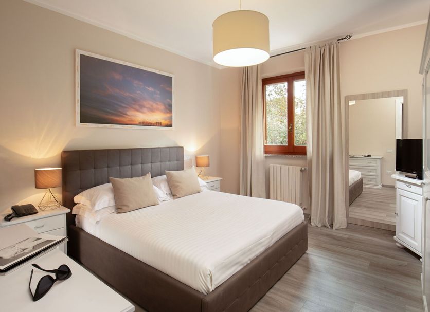 Valle Del Buttero, Capalbio hotel room with double bed, bedside lamps, mirror, and window