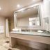 Hotel Clariana San Jose bathroom with vanity, large mirror, toilet, and shower curtain
