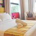 Puteri Bay Hotel in Malacca room with king bed, folded towels, armchair, and large windows