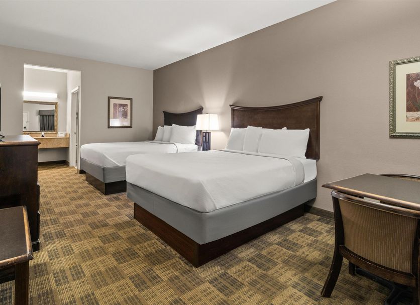 Americas Best Value Inn Byhalia guest room with two beds, desk, and adjoining vanity area