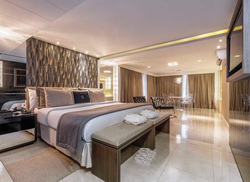 Sj Premium Hotels By Atlantica in Goiânia: spacious suite with king bed, bench, and glossy tiled floor