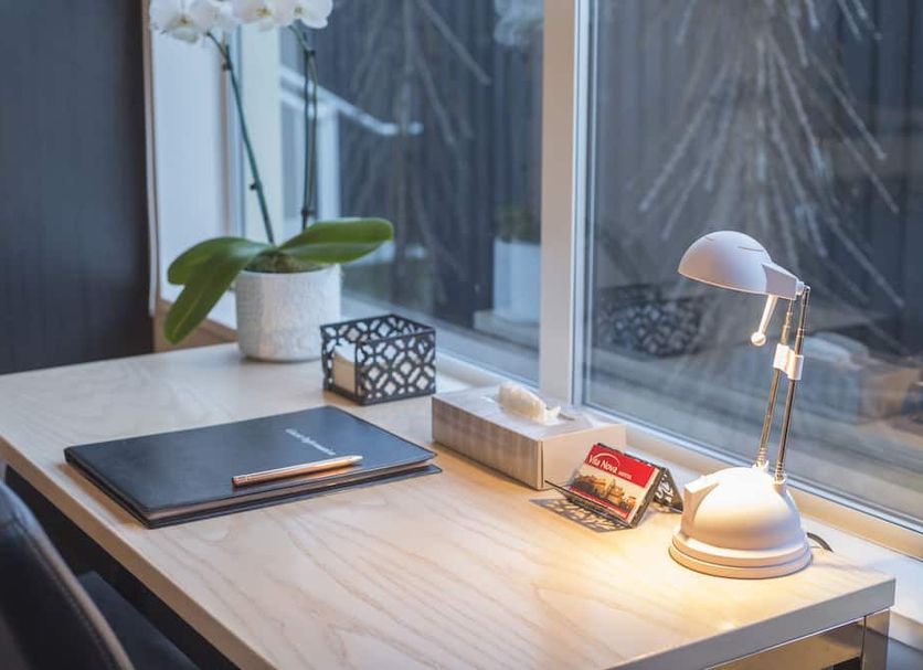 Vita Nova Motel, Christchurch desk by window with lamp, notebook, pencil, tissue box and plant