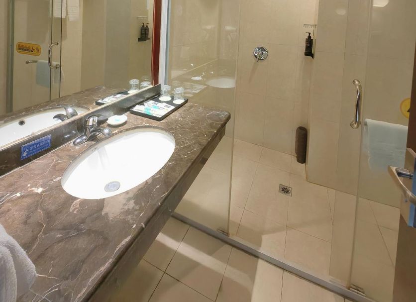Xinji Garden Hotel in Nanchang bathroom with marble vanity, sink, mirror and glass walk-in shower