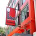 Ideal Hotel Pratunam in Bangkok with red facade, hanging sign, and covered entrance walkway