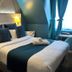 Hôtel Clairefontaine Paris guest room with double bed, teal accents, wall lamps and window drapes