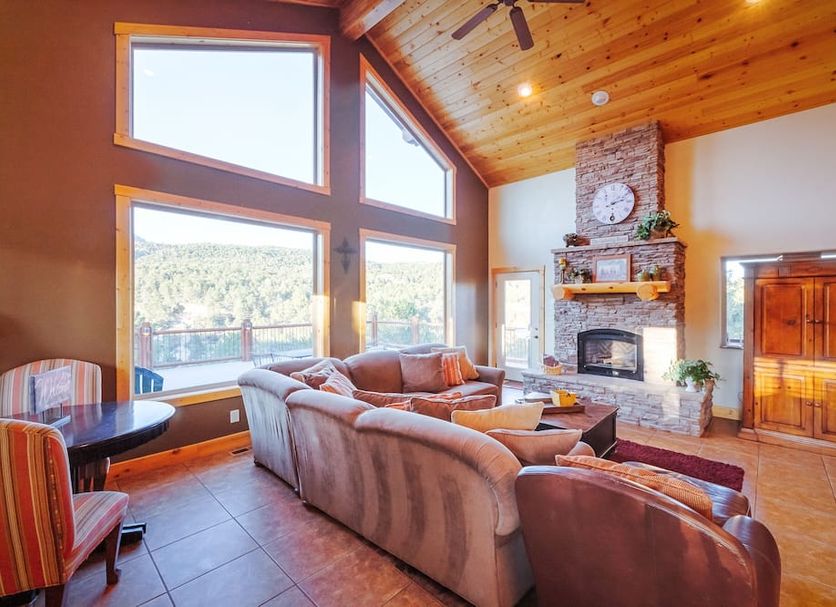 Zion Ponderosa Ranch Resort in Mount Carmel living room with large windows, stone fireplace and mountain views