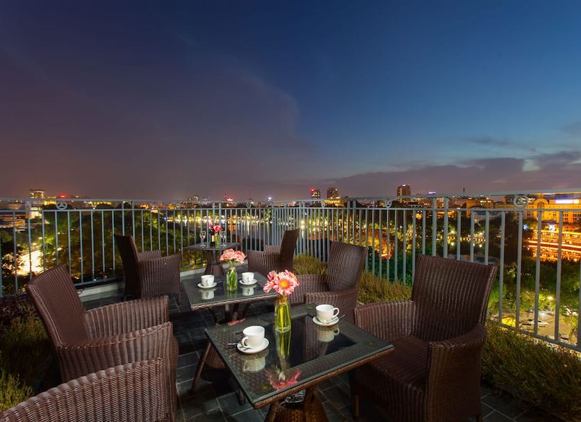 Bella Premier Hotel & Rooftop Skybar in Hanoi: rooftop seating with city lights and skyline views at dusk