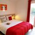 Apartments Antonio in Cavtat bedroom with red bedspread, bedside lamps and balcony door