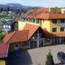 Der Marienhof Hotel Garni in Graz with yellow facade, red-tiled roof, parking lot and mountain views