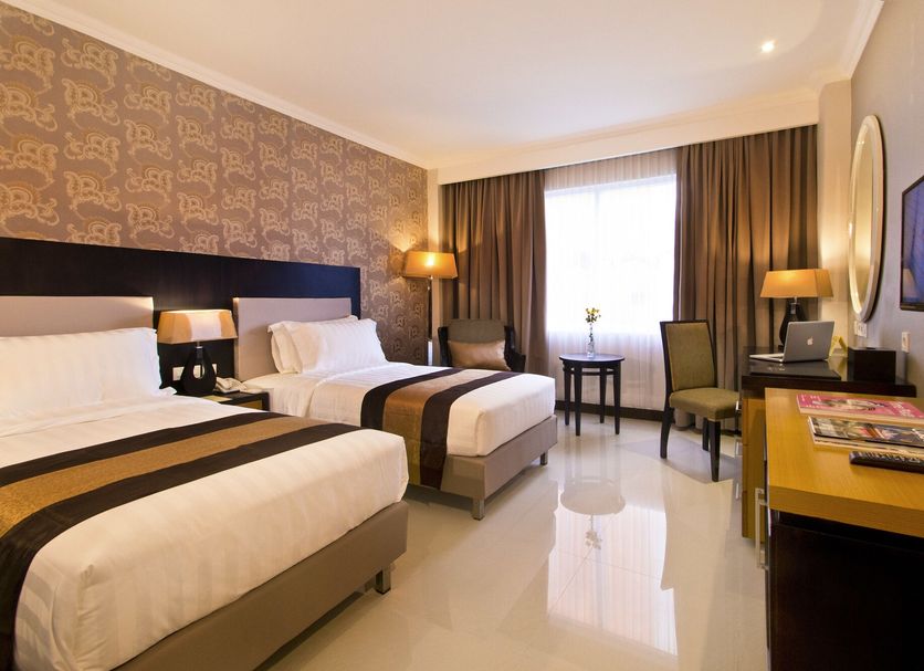 The Victoria Hotel Yogyakarta room with two single beds, desk, chairs, and window view in Yogyakarta