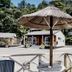 Anchor Lodge Motel in Coromandel with thatched umbrella, patio seating, and tropical hillside surroundings