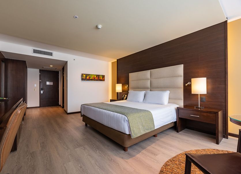Hotel Estelar Milla De Oro Medellín guest room with king bed, desk, and modern wood-accented interior