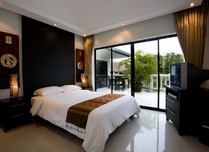 Palm Grove Resort Pattaya bedroom with king bed, balcony, and sliding glass doors to tropical views