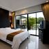 Palm Grove Resort Pattaya bedroom with king bed, balcony, and sliding glass doors to tropical views