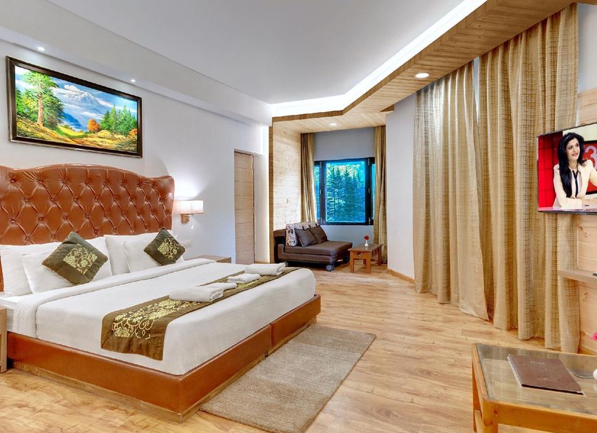 The Orchard Greens Manali room with king bed, lounge chair, wood flooring and forest view