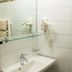 Hotel Vinothek Schwarzer Adler bathroom with sink, mirror, wall-mounted hairdryer and heated towel rack in Ottensheim