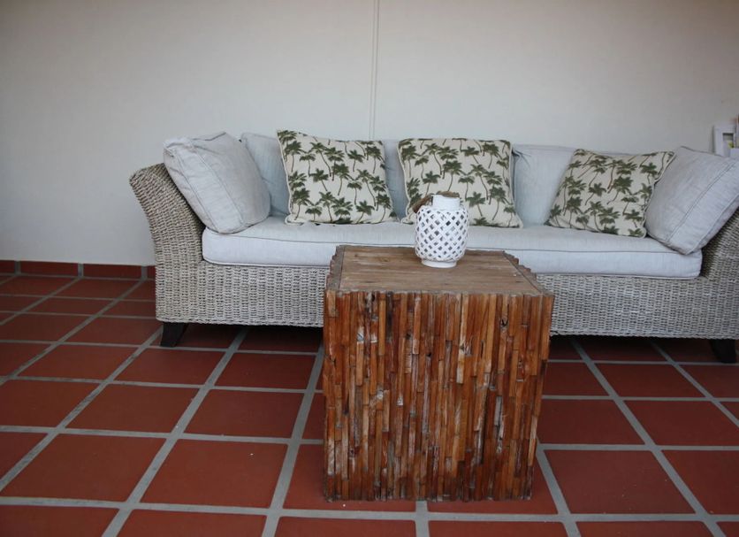 Karibu Aruba in Noord lounge with wicker sofa, patterned cushions and rustic wood coffee table