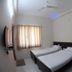 Sr Residency in Tiruchirappalli guest room with two single beds, wall-mounted TV and window curtains