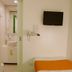 Islands Stay Hotels - Puerto Princesa room with wall-mounted TV, sink area and orange bedspread