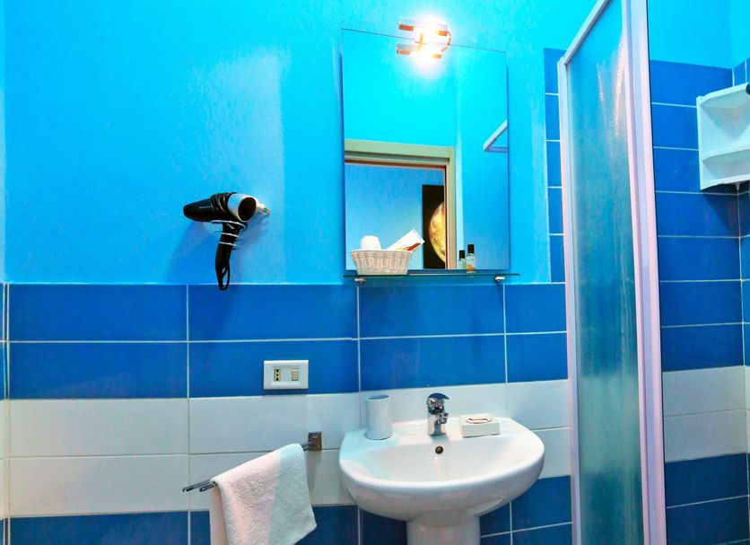 Kosmos Siracusa bathroom with sink, shower, blue tile walls, and mirror