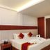 Sathyam Oasis Tiruchirappalli room with king bed, red accents, curtains, chair and mirror