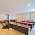 Grand Kuta Hotel and Residence in Kuta meeting room with red chairs, tables, and a projector screen