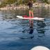 Crown Motel in Kings Beach with a paddleboarder on calm lake water near a rocky shoreline