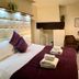 Dolgun Uchaf Guesthouse in Dolgellau bedroom with plush bed, purple bedding, and seating nook