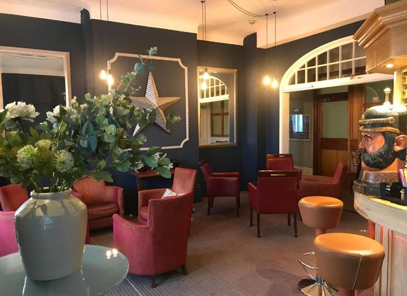 West Rocks Townhouse Eastbourne lounge with red chairs, arched windows and decorative wall art