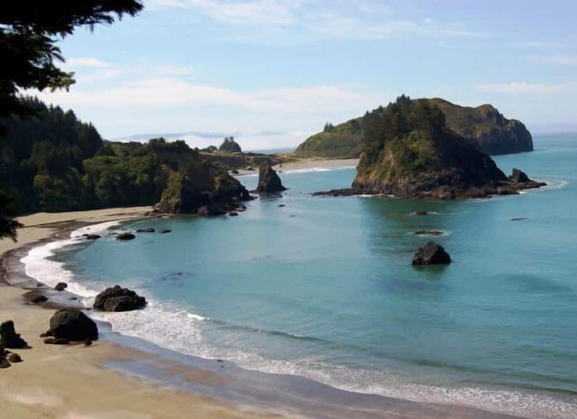 Lookout At Trinidad Bay in Trinidad: oceanfront view of a sandy cove, rocky islet and calm blue bay