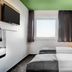 B&B Hotel Baden-Airpark in Rheinmunster guest room with twin beds, window, wall-mounted TV and green ceiling.
