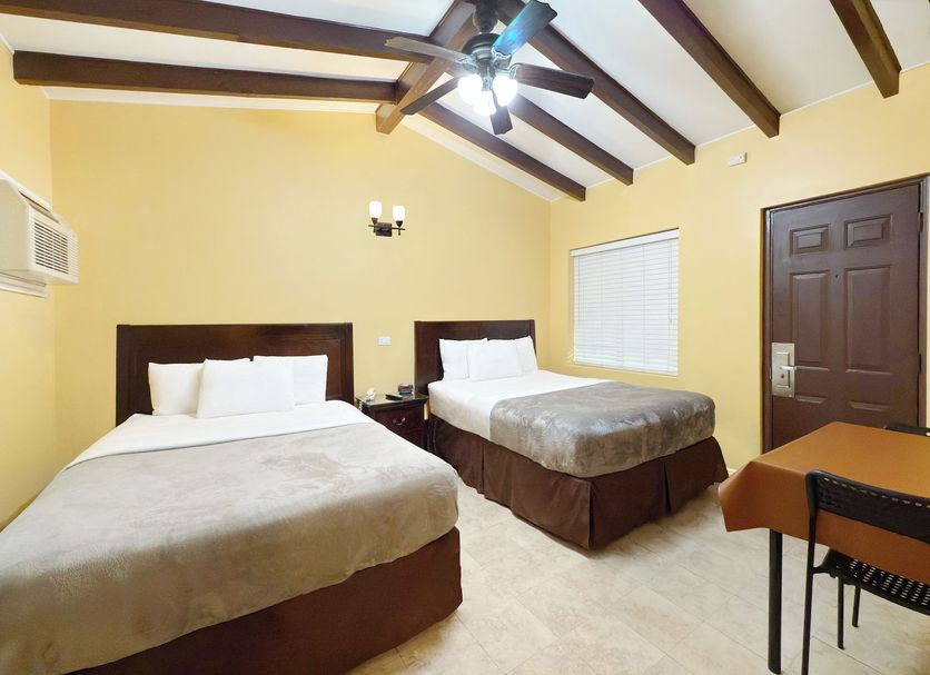 El Patio Inn in Los Angeles guest room with two beds, ceiling fan, and table